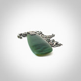 This photo shows a drop pendant suspended from a silver clasp and silver chain. The jade is a lovely light chatoyant Inanga jade with subtle leaf patterned sterling silver on the front. A lovely chatoyant New Zealand Inanga jade pendant carved for us by Josey Coyle.